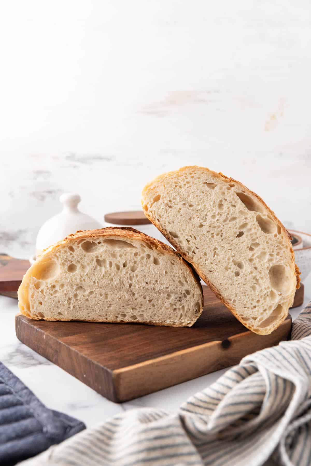 A loaf of sourdough bread that has been sliced in half on a wooden cutting board.