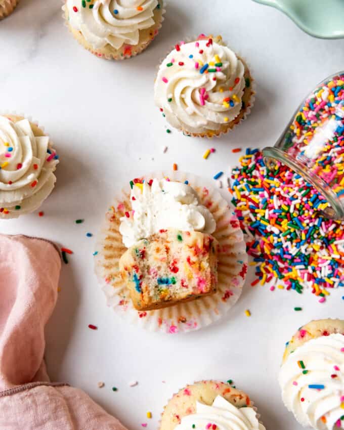 An overhead image of a frosted sprinkle cupcake with a bite taken out of it.