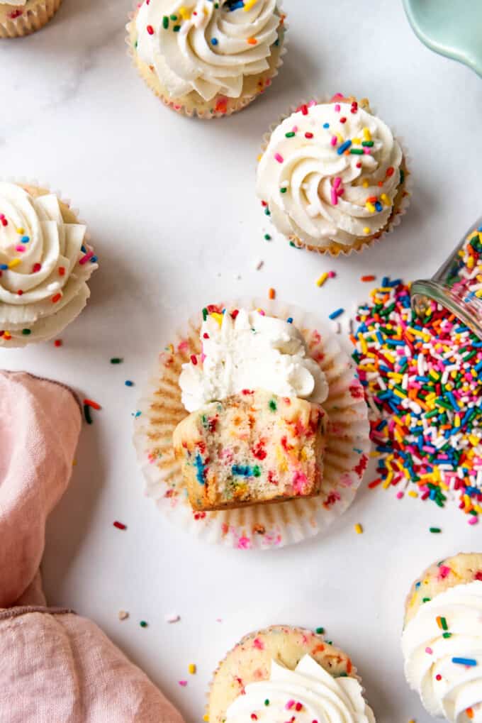 A close image of a funfetti cupcake with a bite taken out of it.