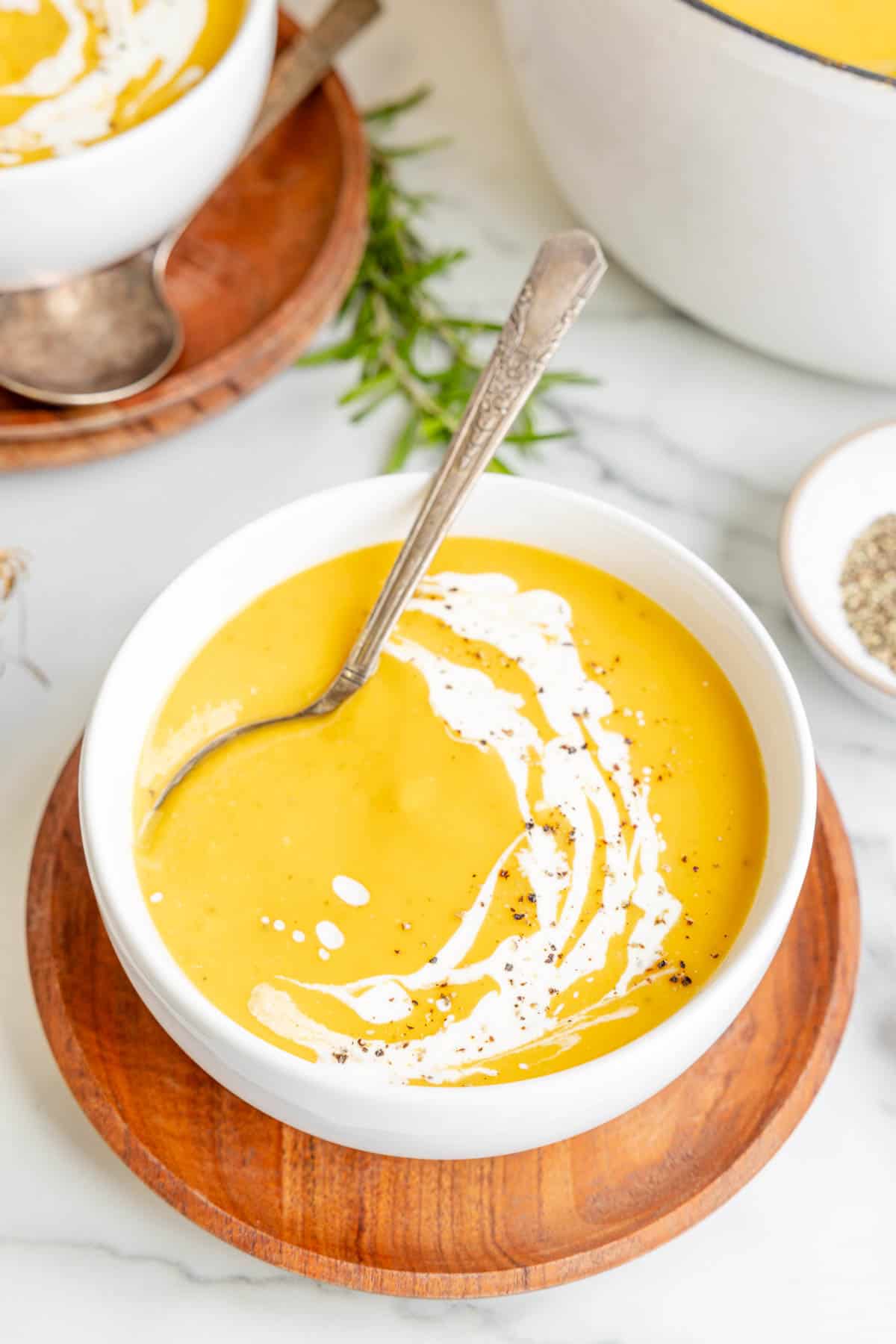 A bowl of butternut squash soup with a spoon in it.
