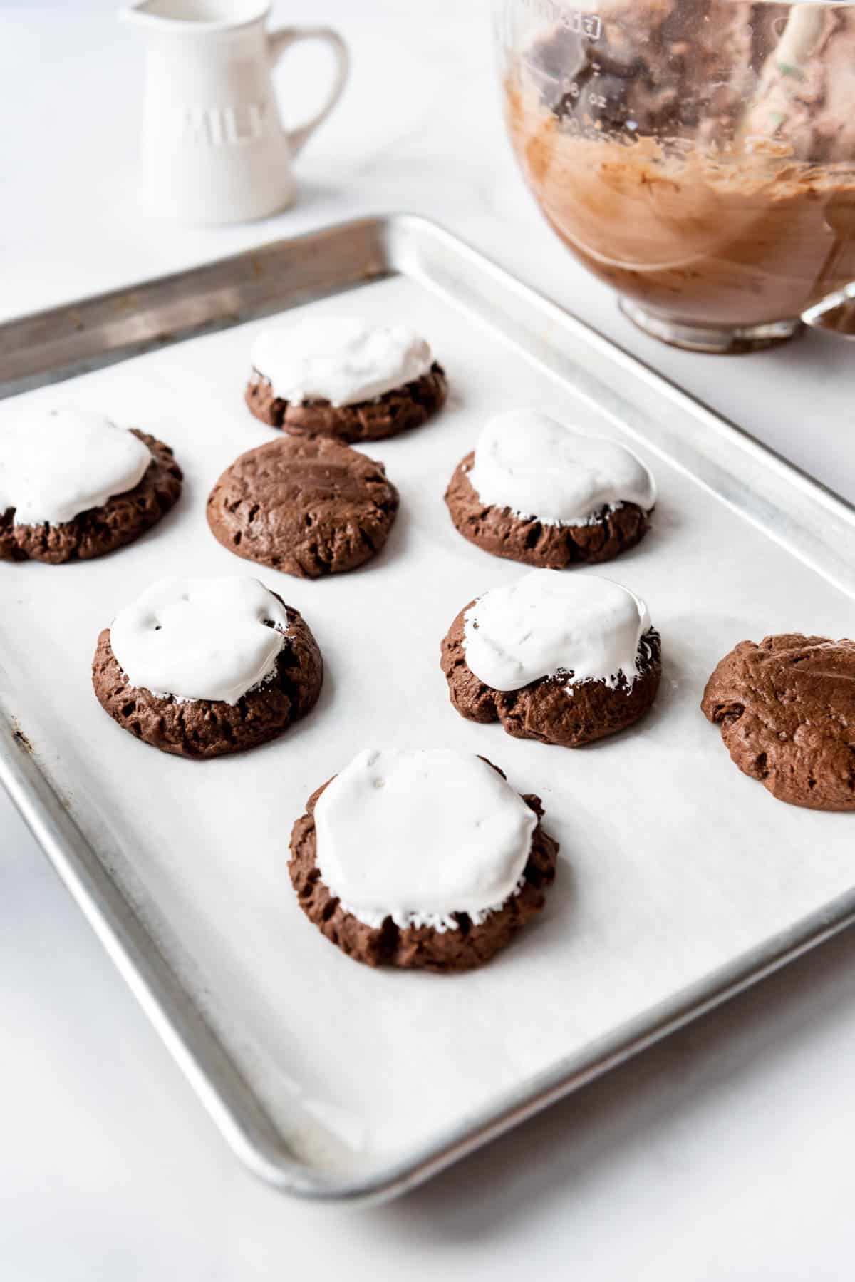 Topping chocolate cookies with marshmallow fluff.