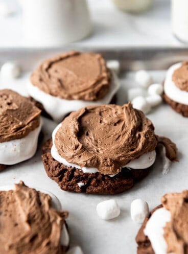Soft chocolate cookies topped with marshmallow fluff and chocolate frosting surrounded by miniature marshmallows.