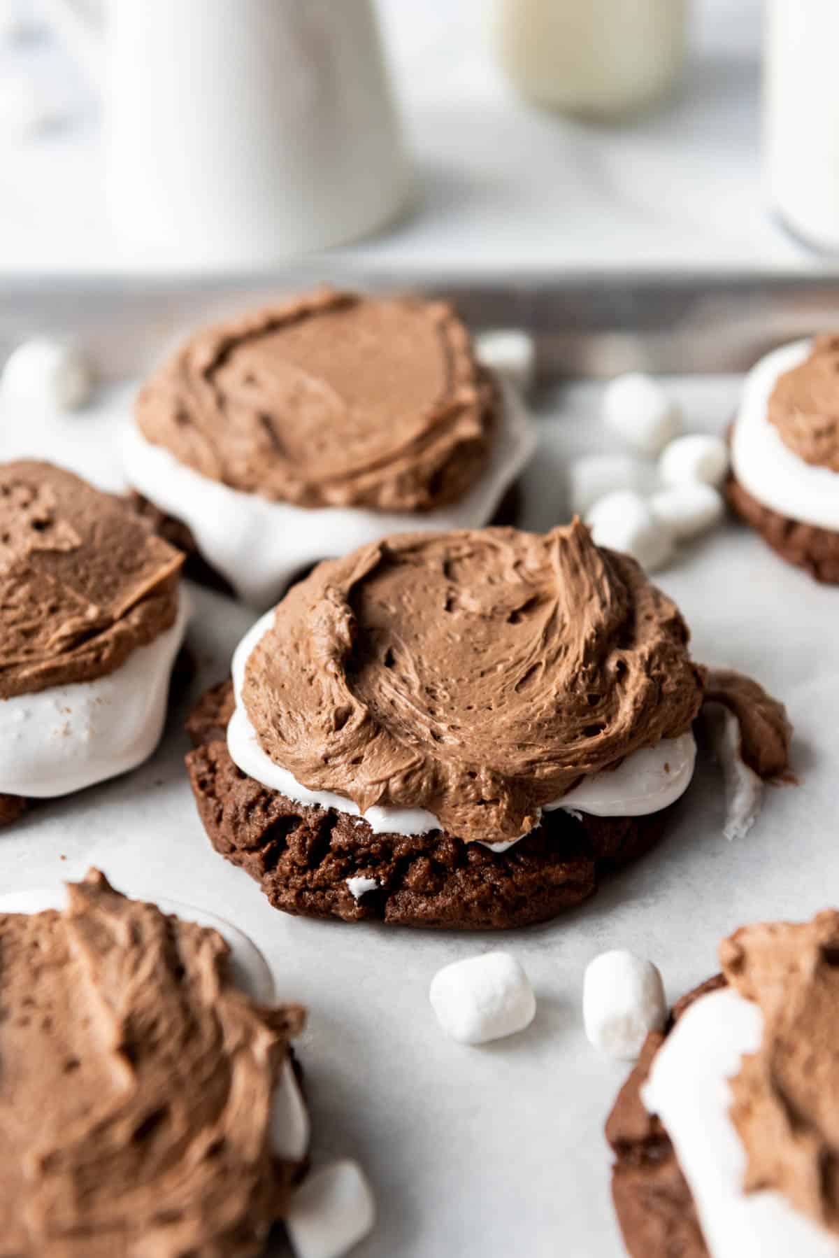 Soft chocolate cookies topped with marshmallow fluff and chocolate frosting surrounded by miniature marshmallows.