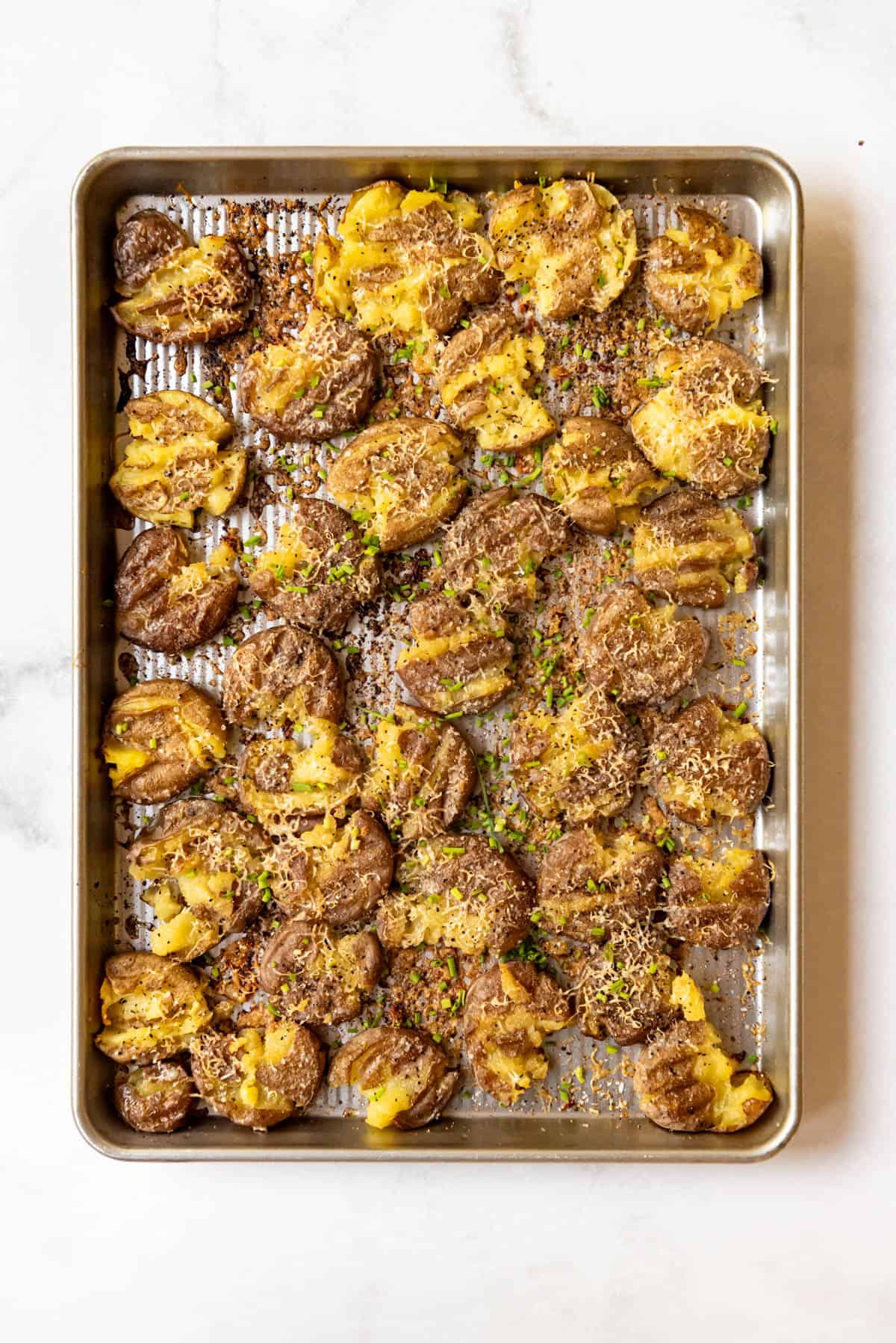 An overhead image of a baking sheet full of crispy smashed potatoes.