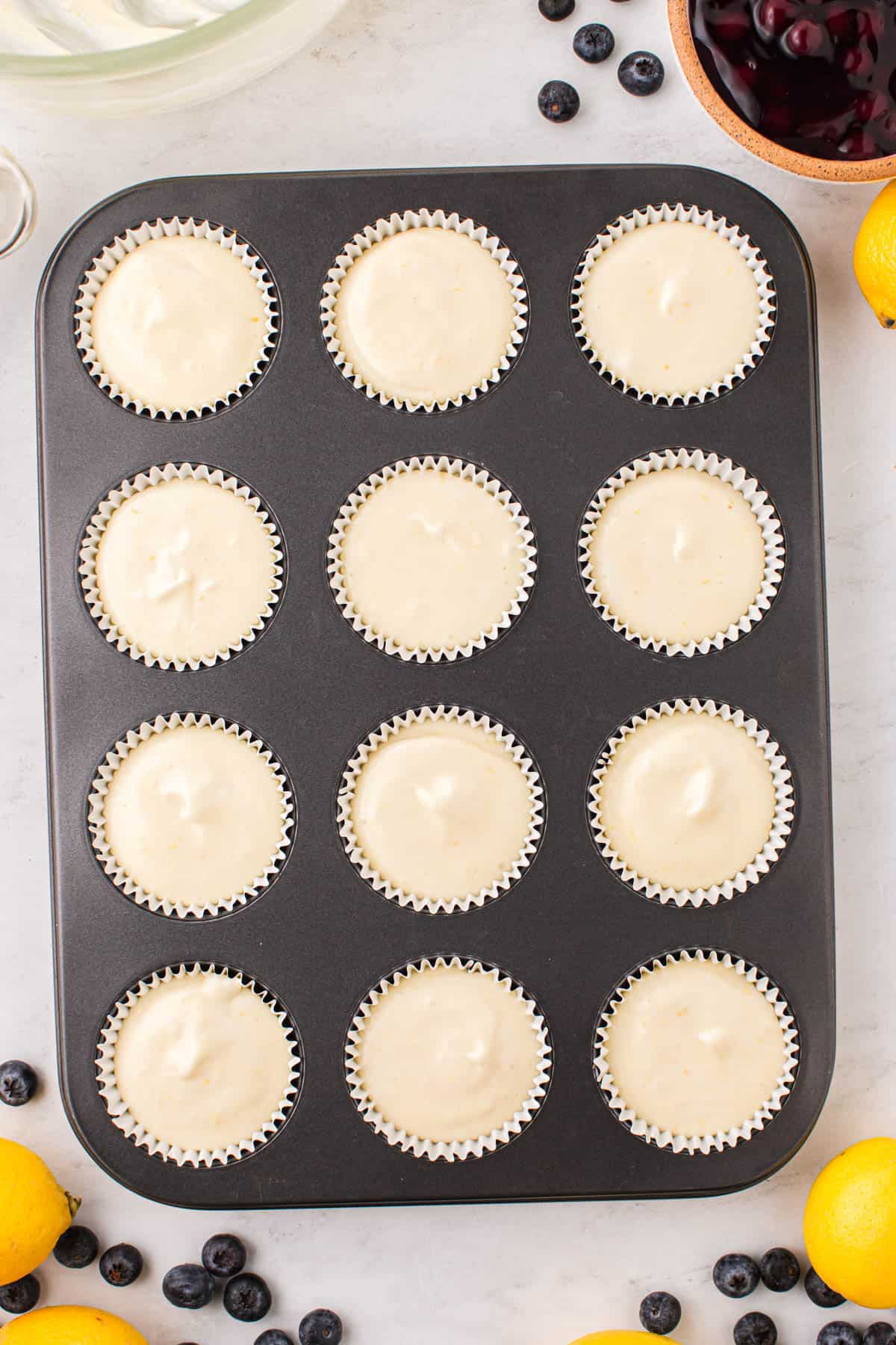Dividing cheesecake batter between cups of a muffin pan.