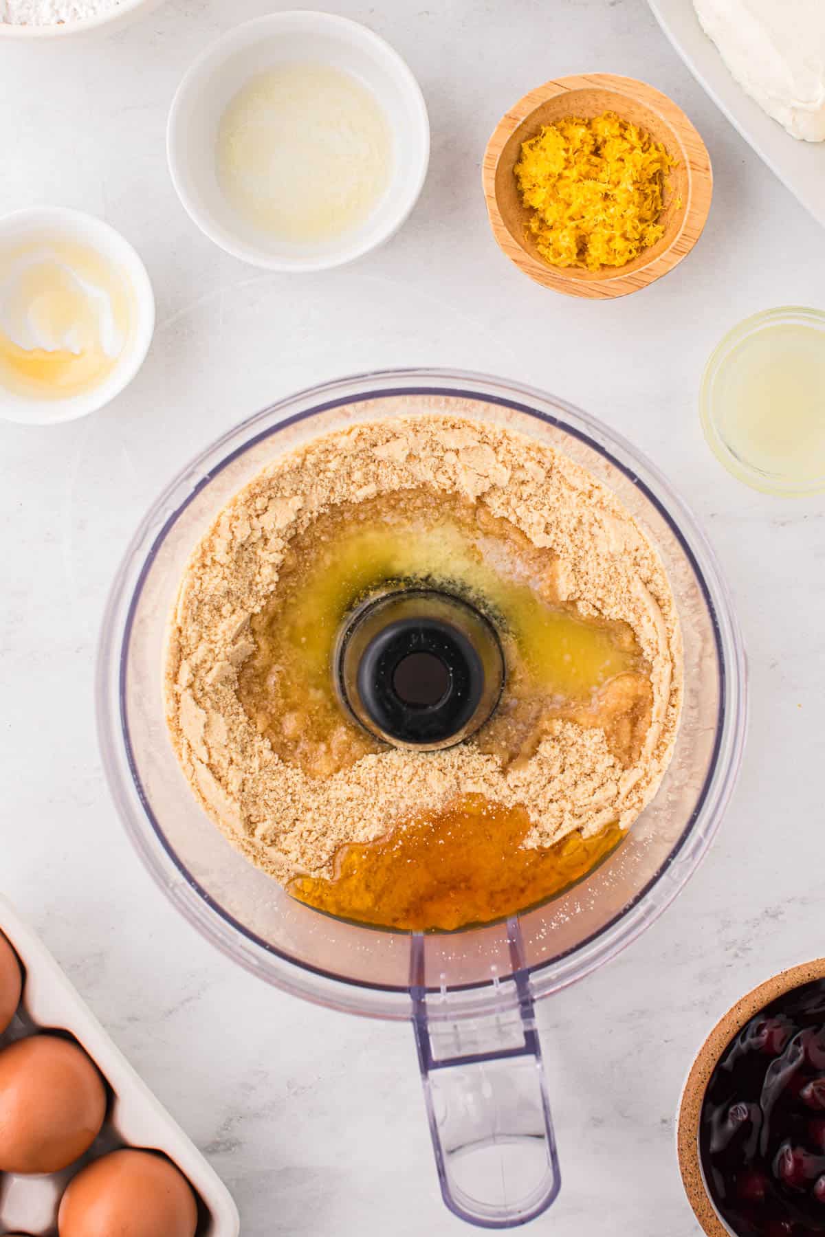 Combining ingredients for cheesecake crust  in a food processor.
