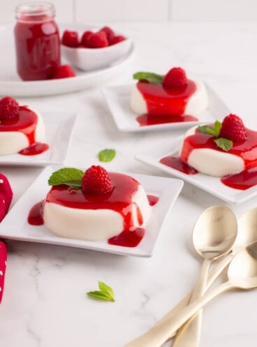 Plates with individual servings of panna cotta with raspberry sauce.