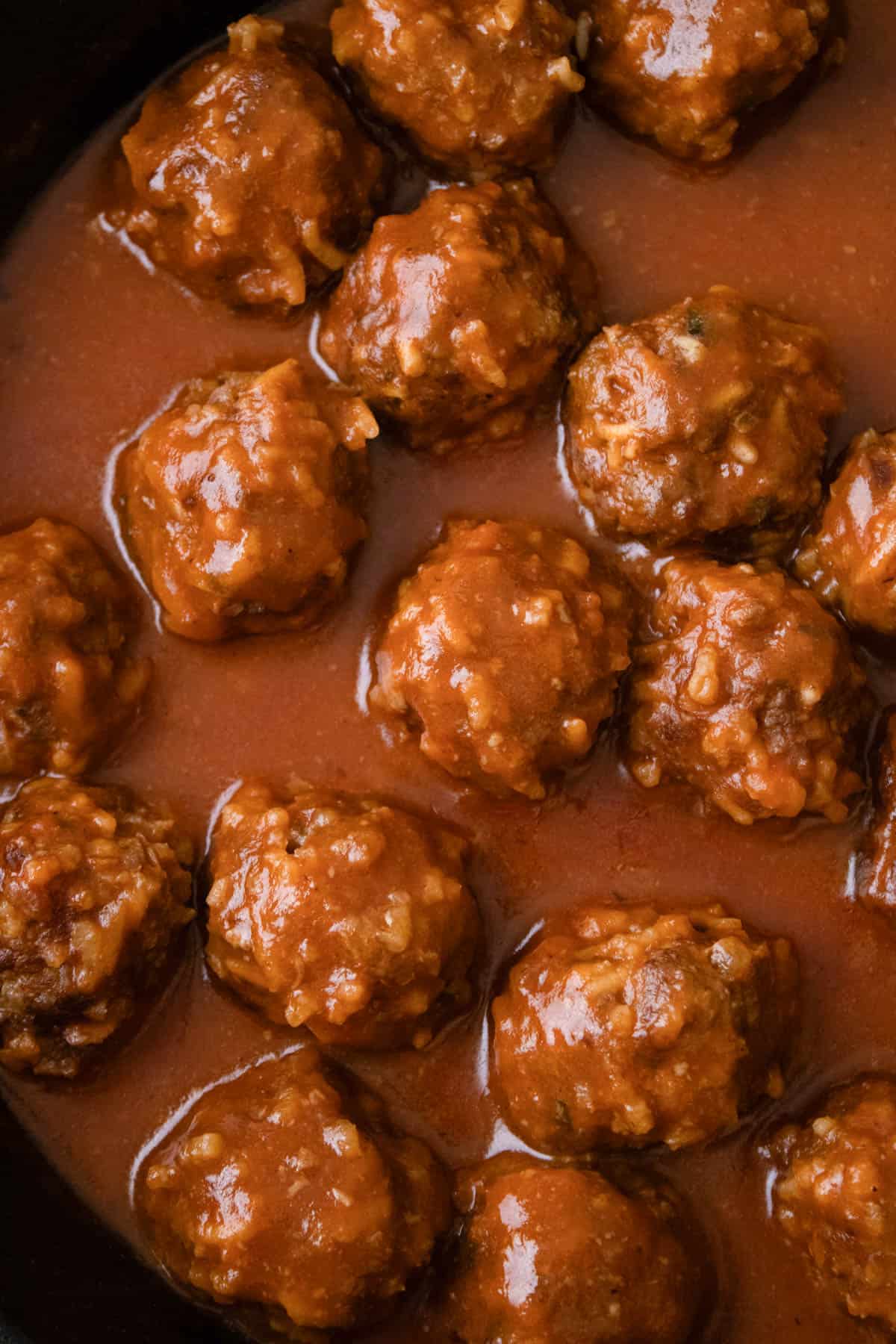 A close up image of porcupine meatballs in a savory tomato sauce.