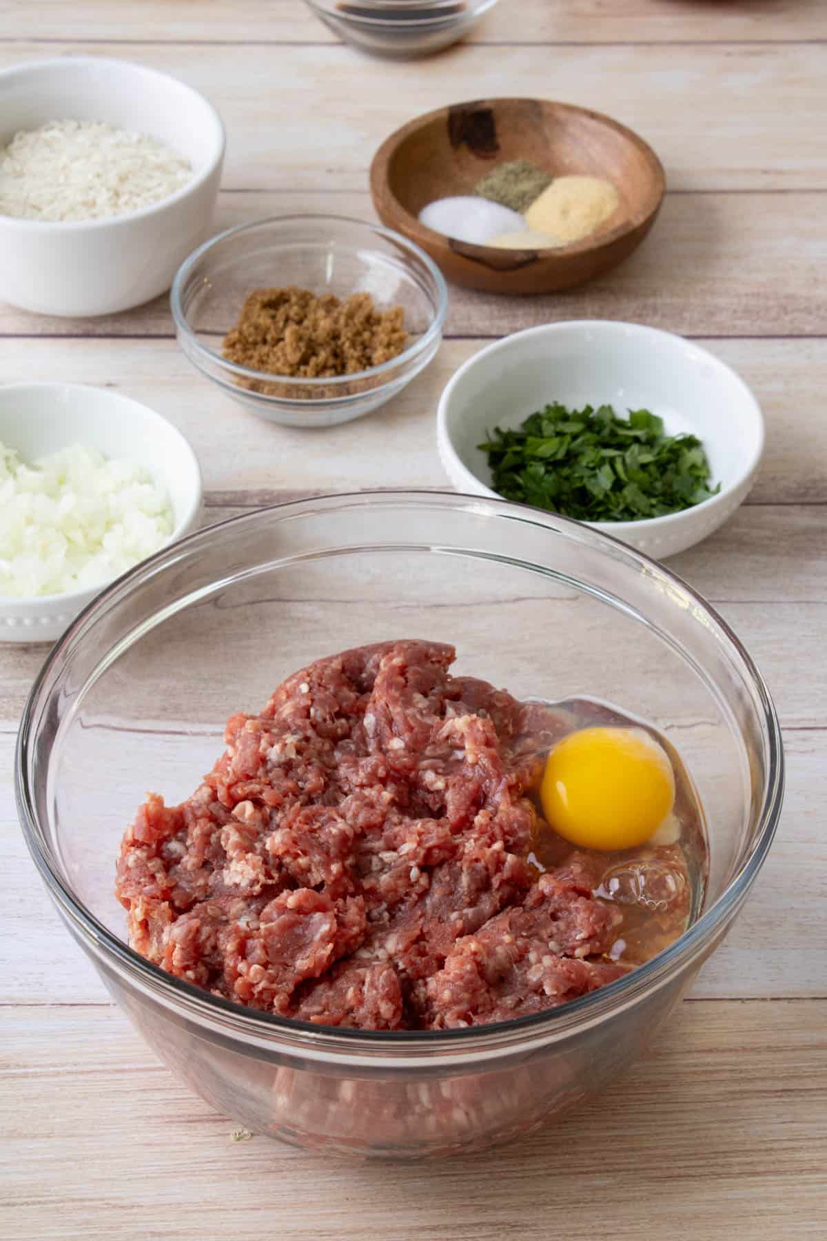 Combining an egg and ground beef in a bowl.