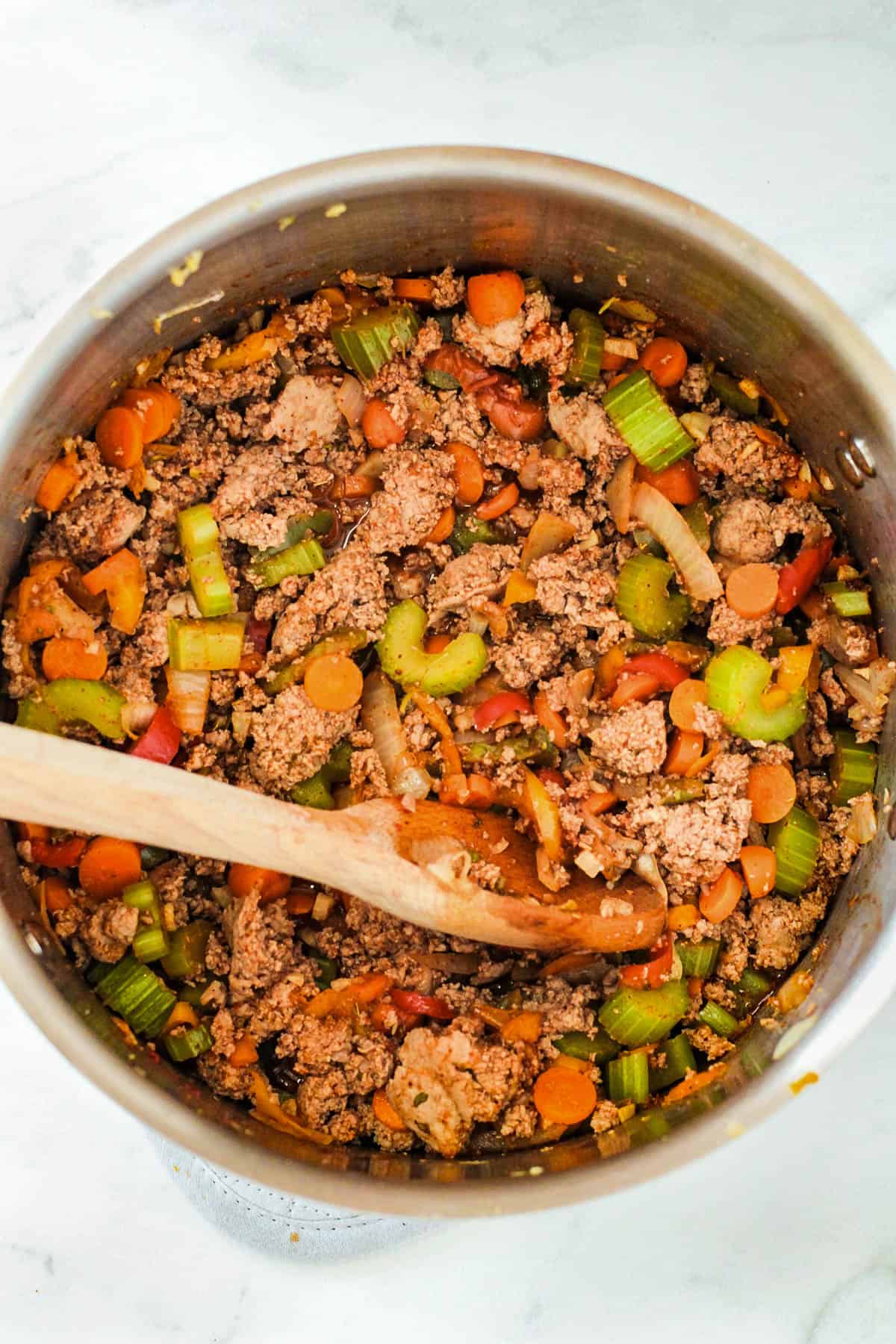 Combining veggies and browned ground turkey in a large pot.