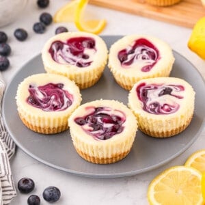 Cooled mini lemon blueberry cheesecakes on a plate.