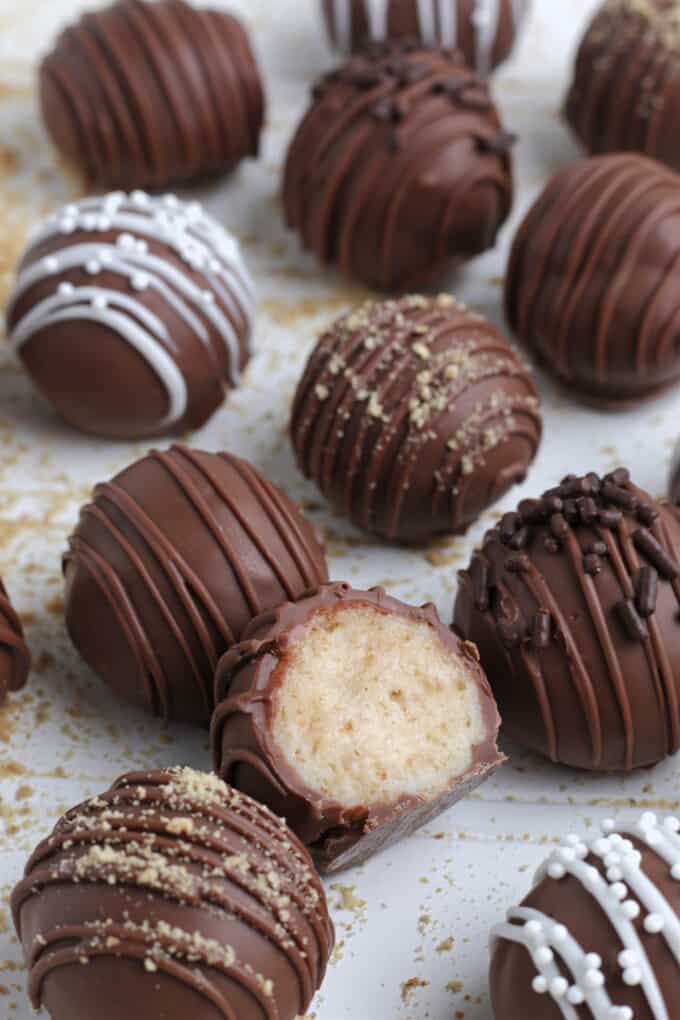 A cheesecake truffle that has been cut in half with more truffles around it.