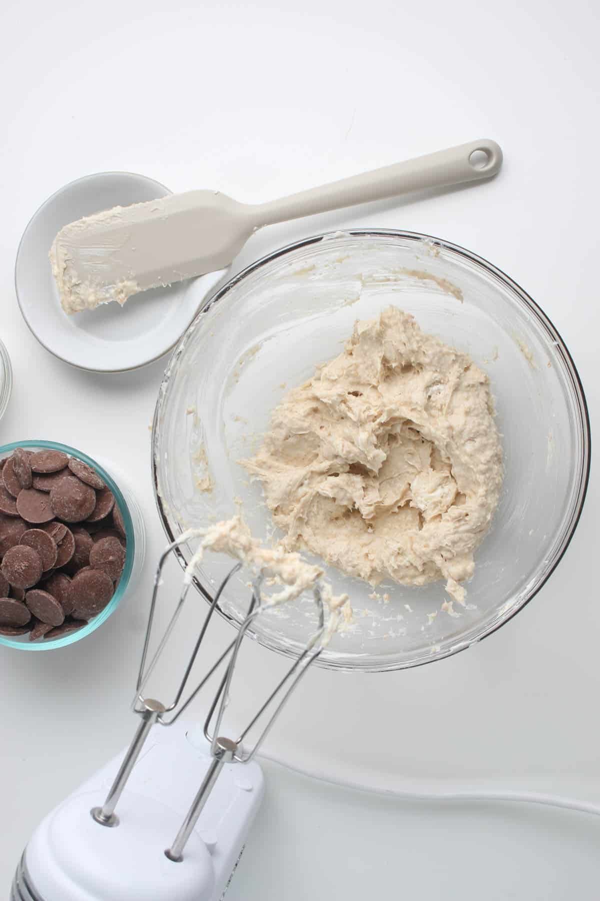 Mixing cheesecake truffle ingredients together in a bowl with a hand mixer.