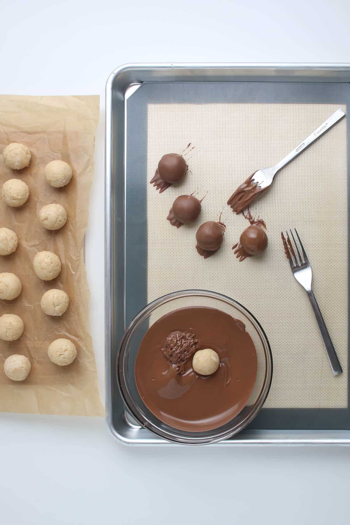 Dipping cheesecake truffles in melted chocolate.