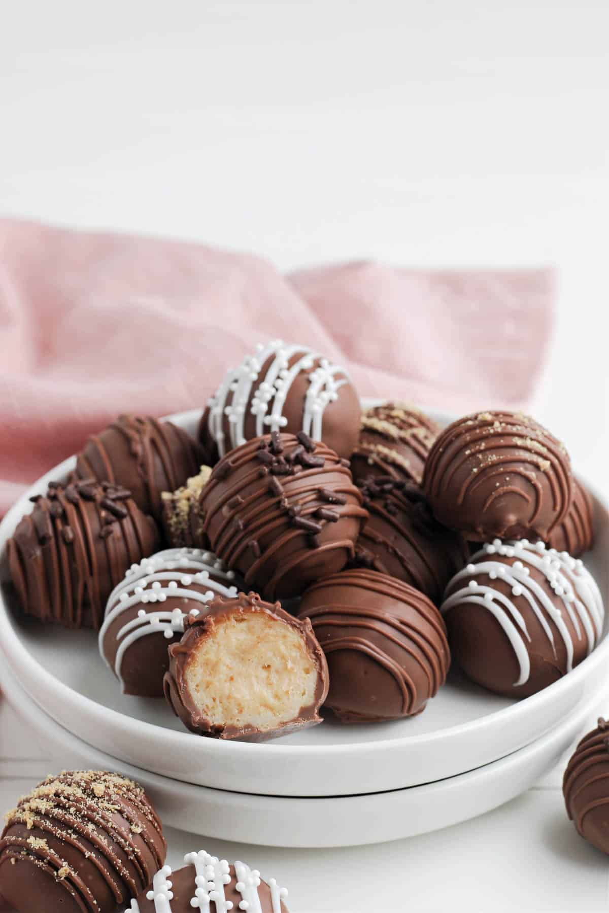 A plate of cheesecake truffles with a pink linen napkin behind them.