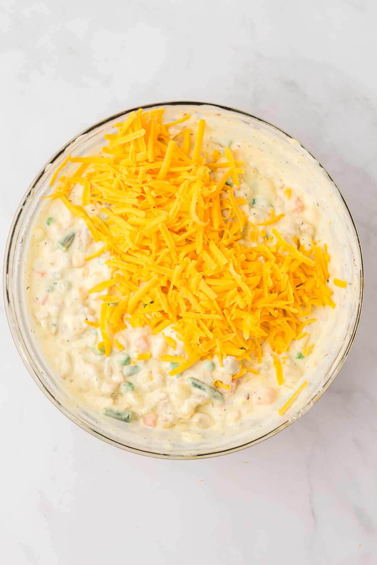 Adding shredded cheese to casserole filling.