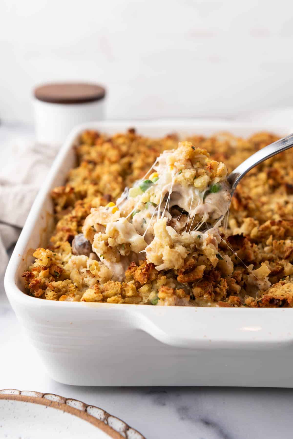 An image of a scoop of chicken and stuffing casserole being lifted out of the baking dish.