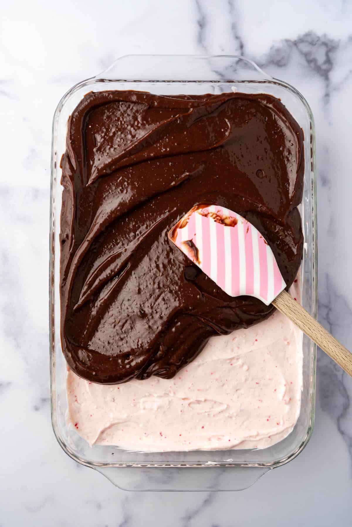 Spreading a layer of chocolate pudding over a peppermint layer.
