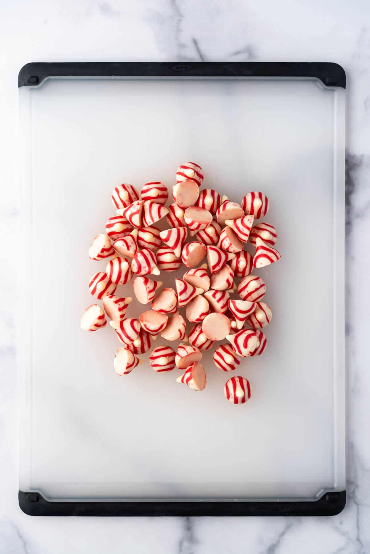 Unwrapped Hershey's candy cane kisses on a cutting board.