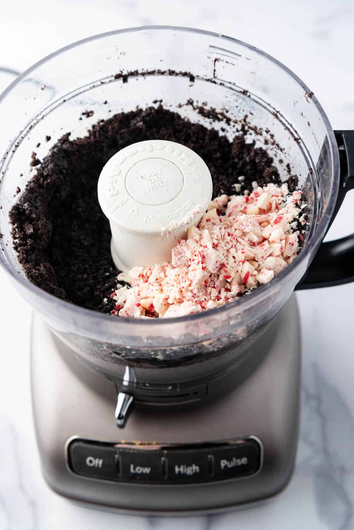 Adding chopped Hershey's candy cane kisses to finely crushed Oreo cookie crumbs in a food processor.