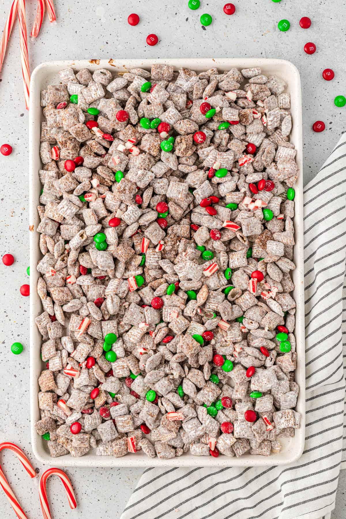 Spreading out the Christmas puppy chow on a baking sheet.