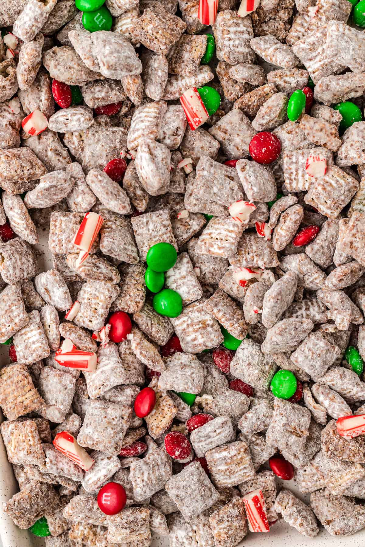 An overhead image of Christmas Chex Mix Muddy Buddies spread on a baking sheet.