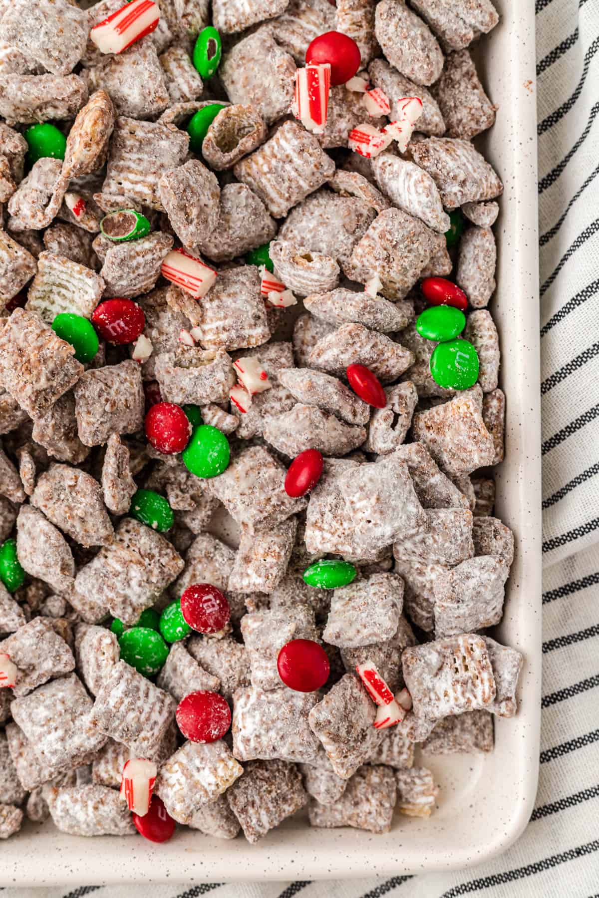 Christmas muddy buddies spread out on a baking sheet.