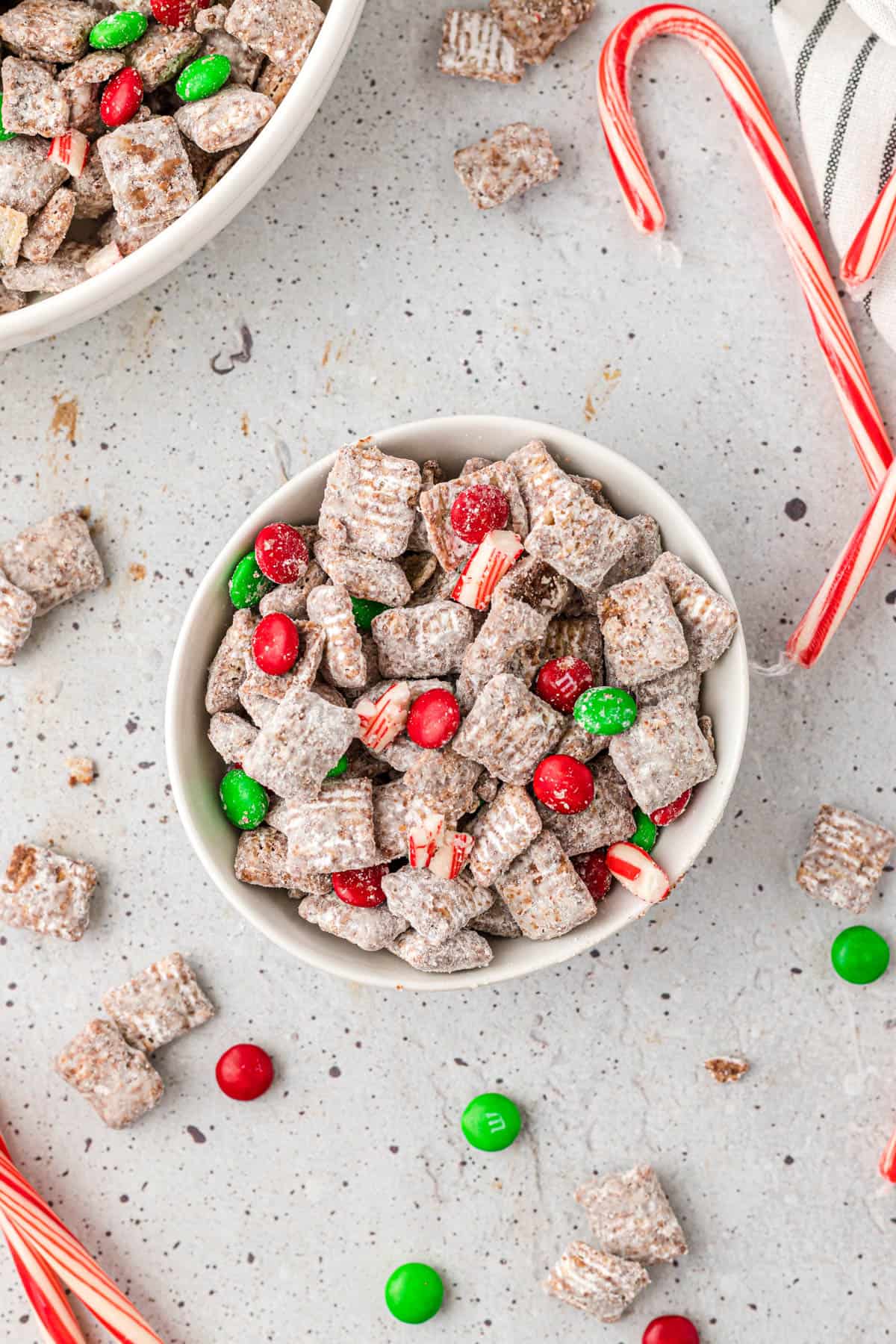 A bowl of Christmas puppy chow made with candy canes and red and green M&Ms.