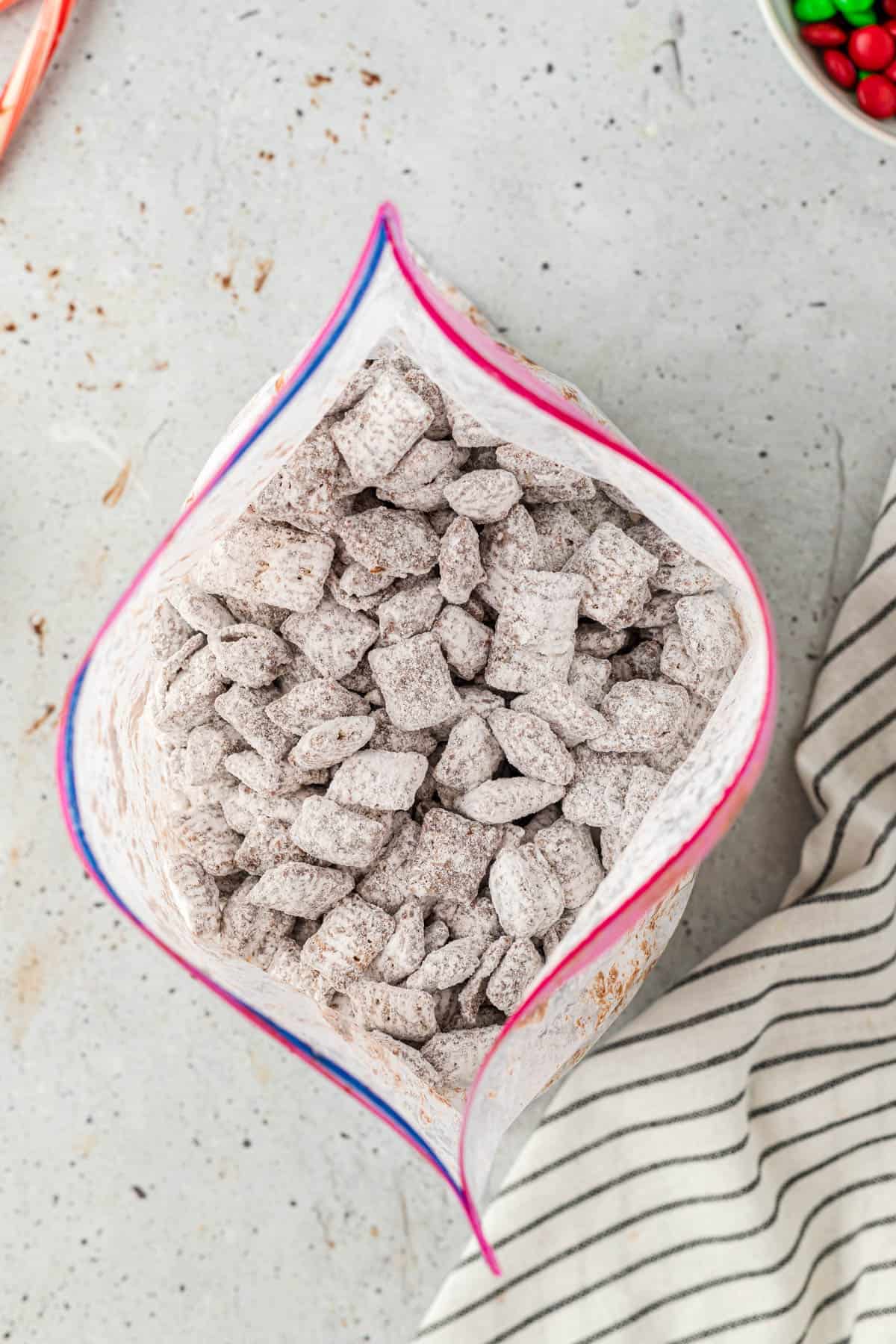 Chex Mix puppy chow that has been coated with powdered sugar in a bag.