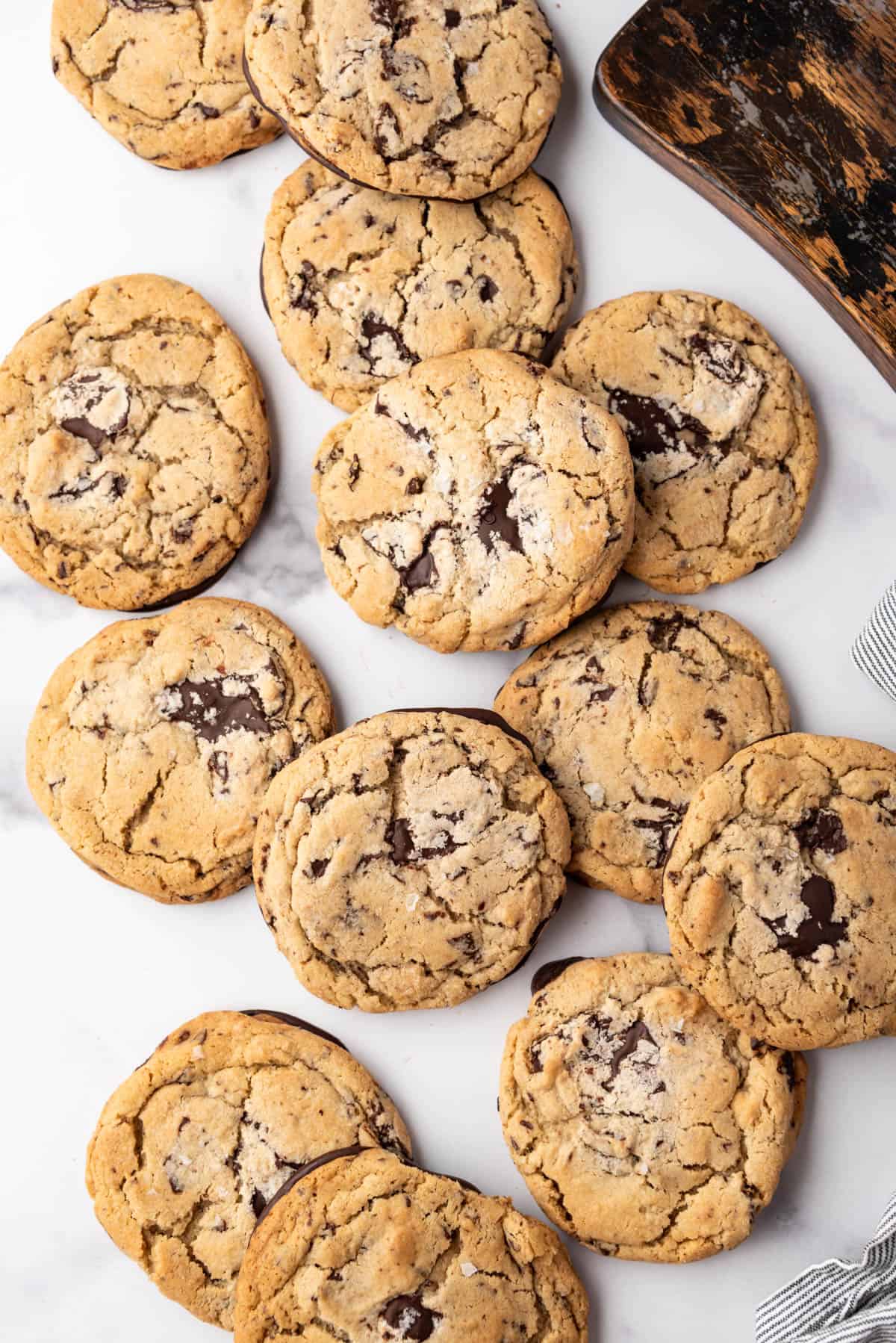 An overhead image of Jacques Torres chocolate chip cookies scattered on a white marble surface.