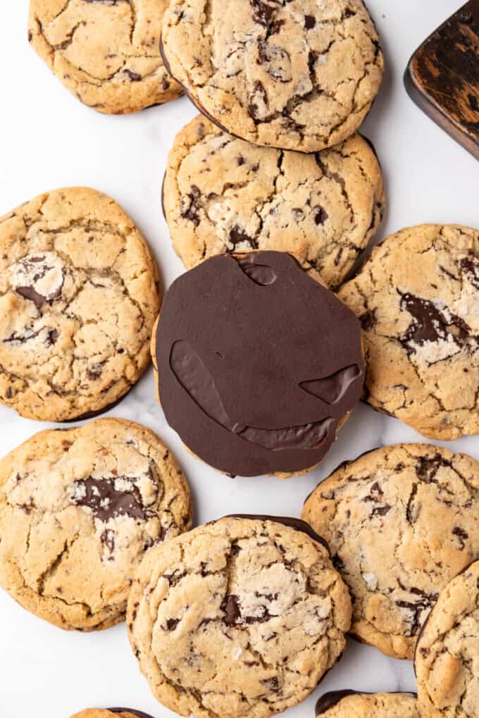 An overhead image of Jacques Torres chocolate chip cookies with one turned over to show the chocolate coated bottom.