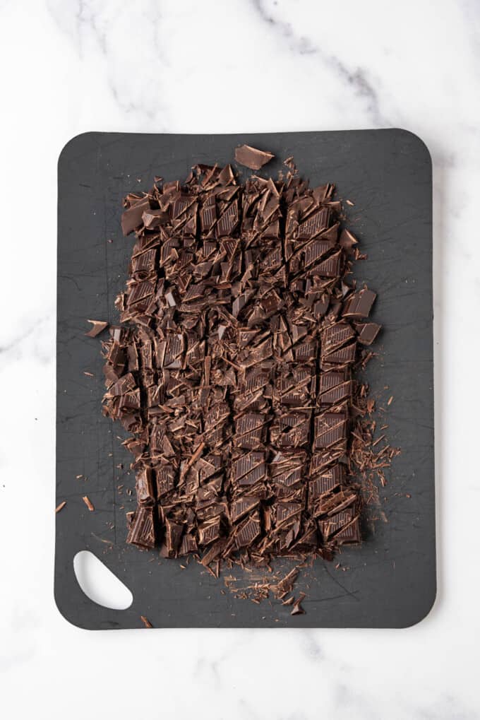 Chopped dark chocolate chunks on a cutting board.