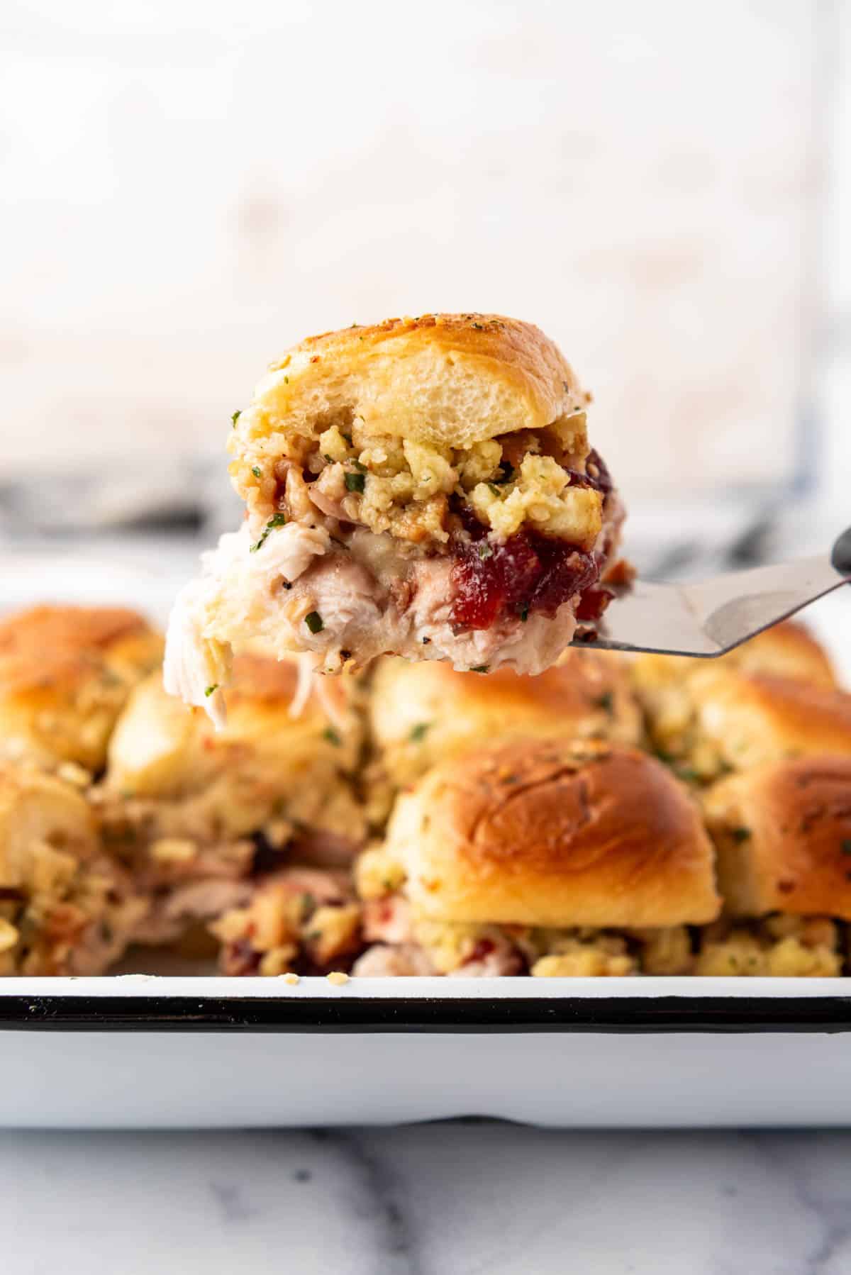 A leftover turkey slider being lifted out of the pan with a spatula.