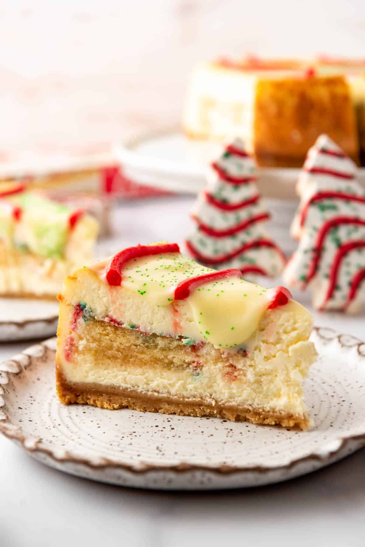 A slice of Little Debbie Christmas Tree Cheesecake on a plate in front of more Christmas Tree Cakes.