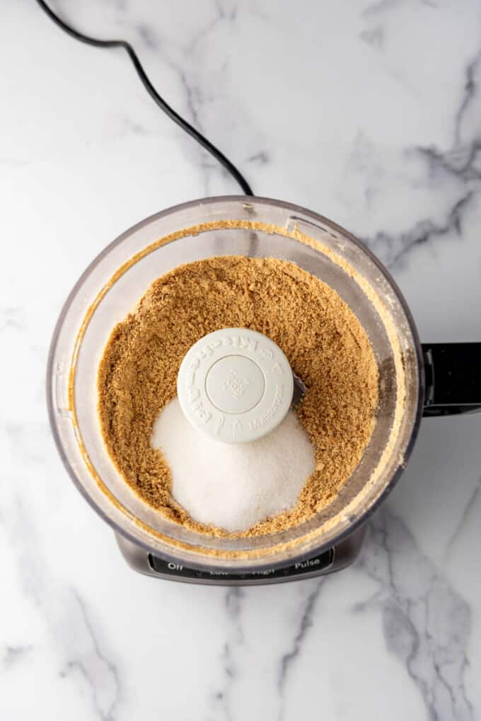 Combinaison de miettes de biscuit Graham écrasées et de sucre dans un robot culinaire.