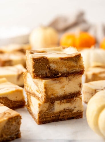 Pumpkin cheesecake bars stacked on top of each other.