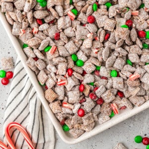 An overhead image of Christmas puppy chow with candy canes and M&Ms.