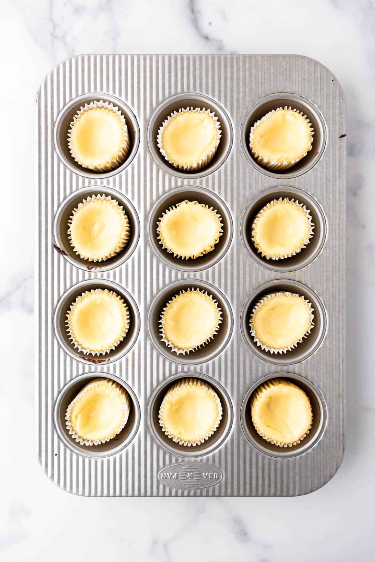 Baked cheesecake tarts in a muffin pan.