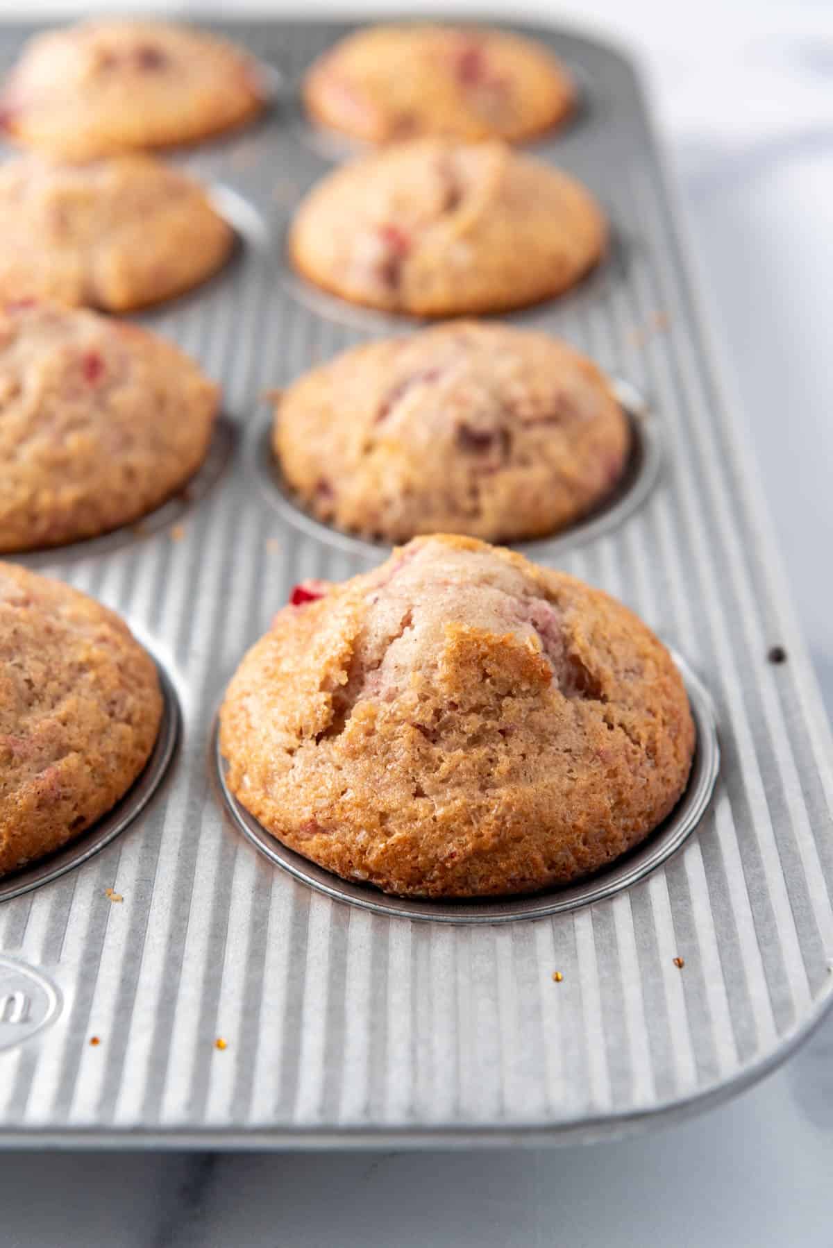 A close image of baked cranberry sauce muffins in a muffin pan.