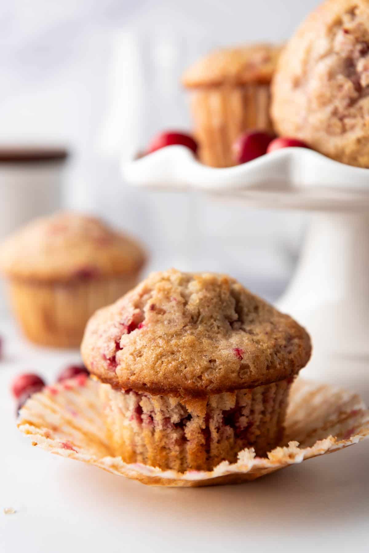 An unwrapped cranberry sauce muffin on a white surface.