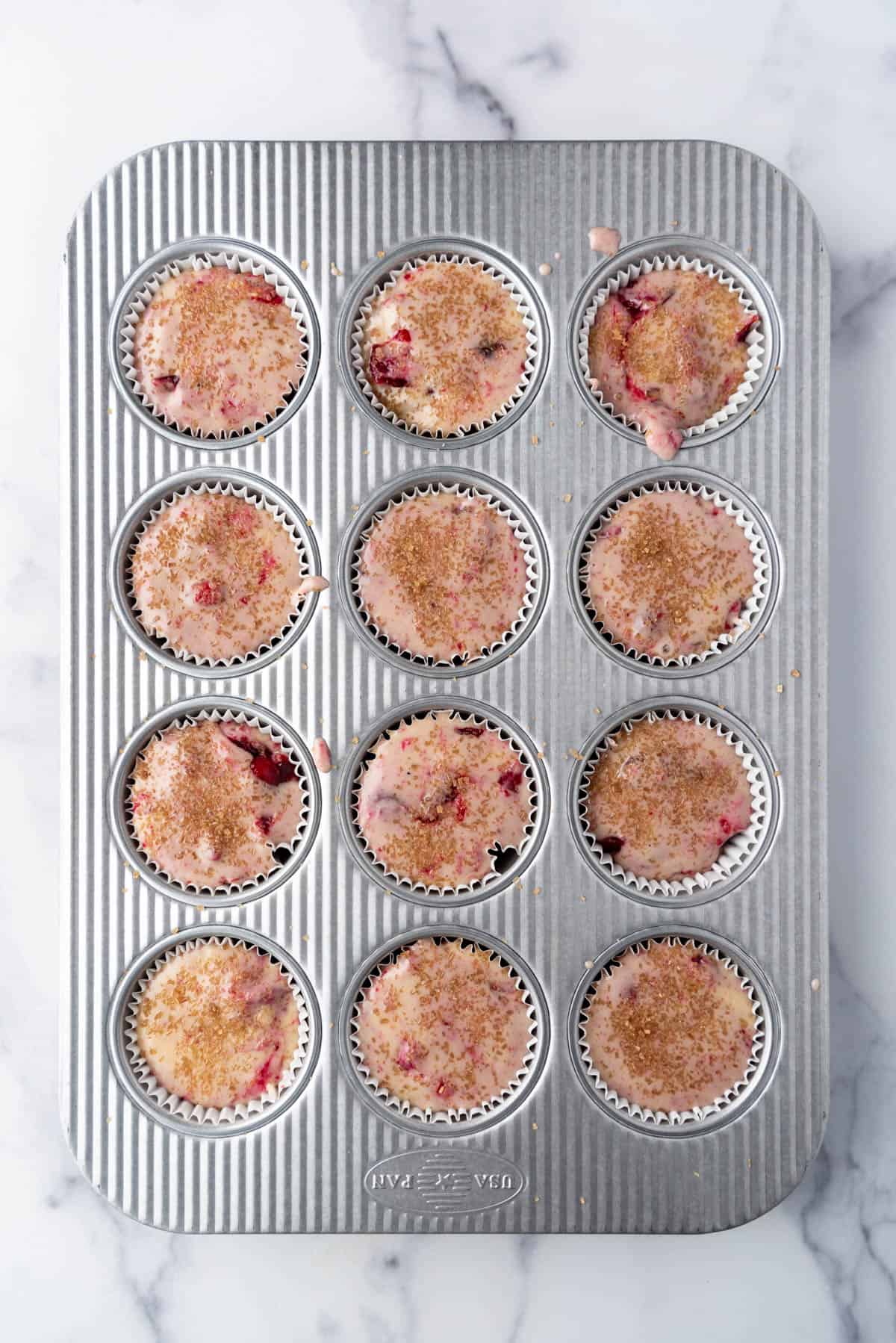 Unbaked muffin batter in a muffin pan ready to be baked in the oven.