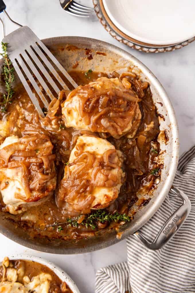 An overhead image of french onion pork chops in a pan with caramelized onions on top.