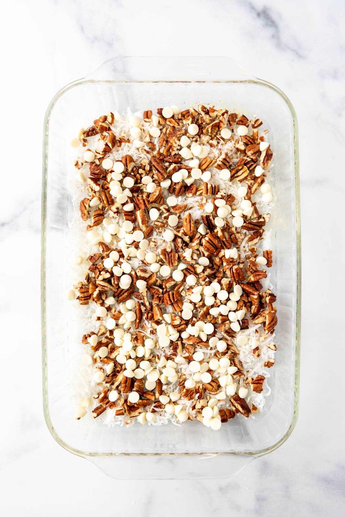 Coconut pecans, and white chocolate chips in a glass baking dish.