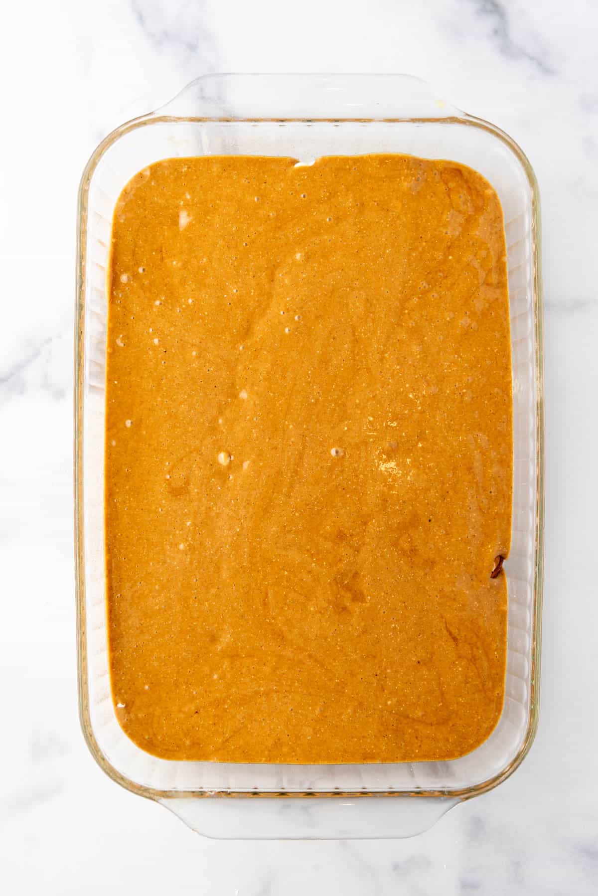 Gingerbread cake batter in a glass baking dish.