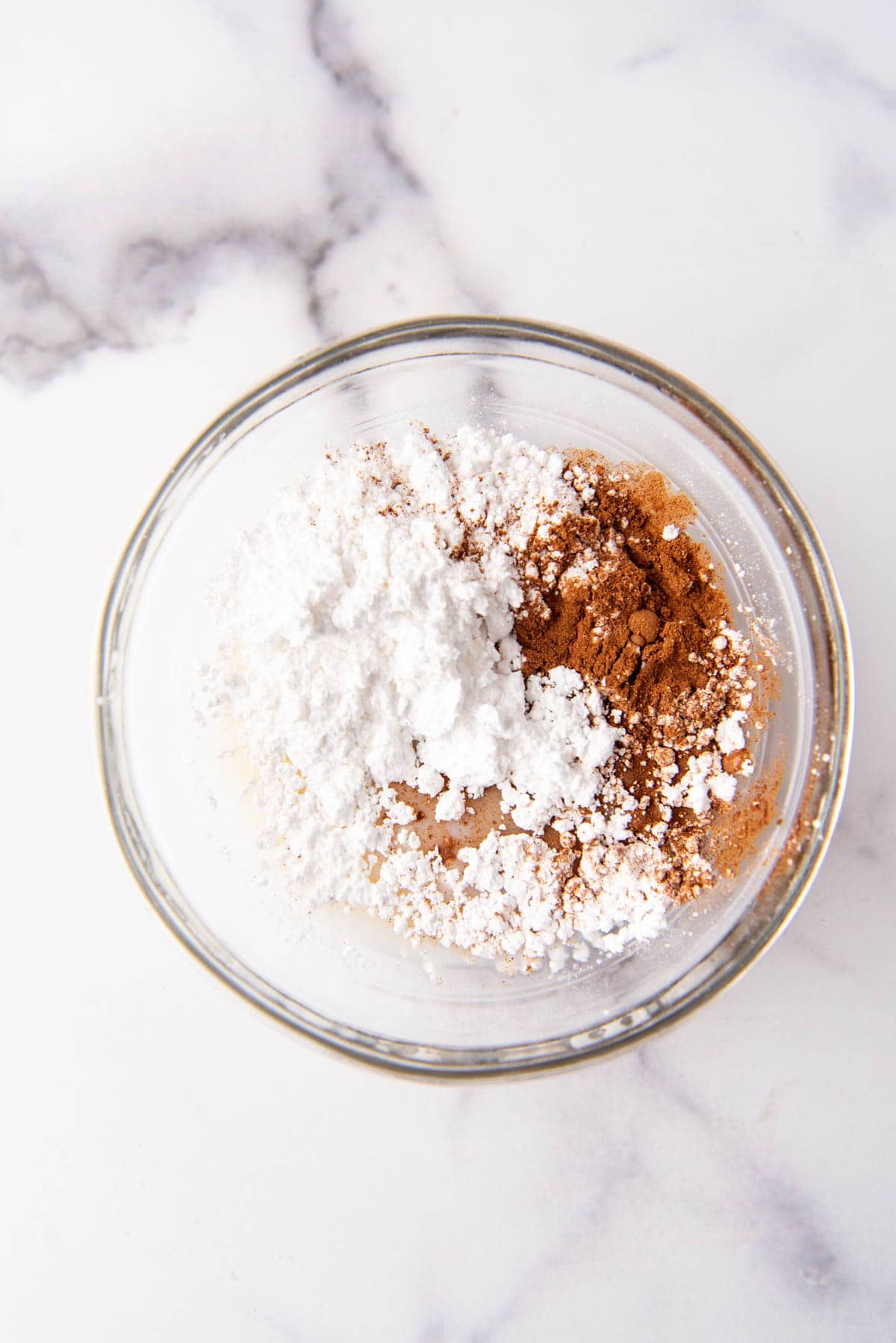 Powdered sugar, ground cinnamon, vanilla extract, and milk in a bowl.