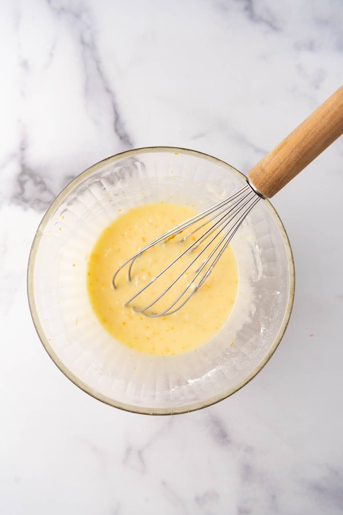 Orange citrus glaze in a bowl with a whisk.