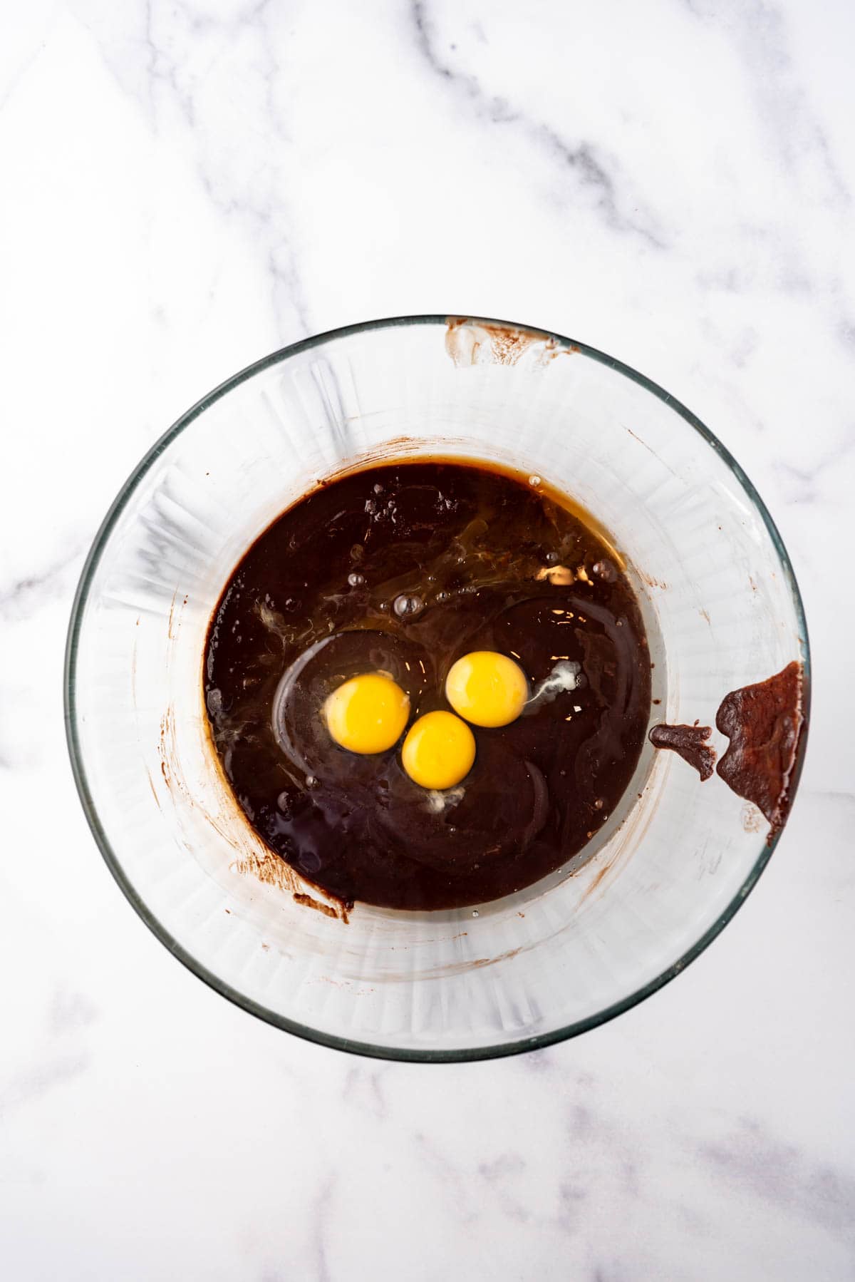 Adding three eggs to brownie batter.