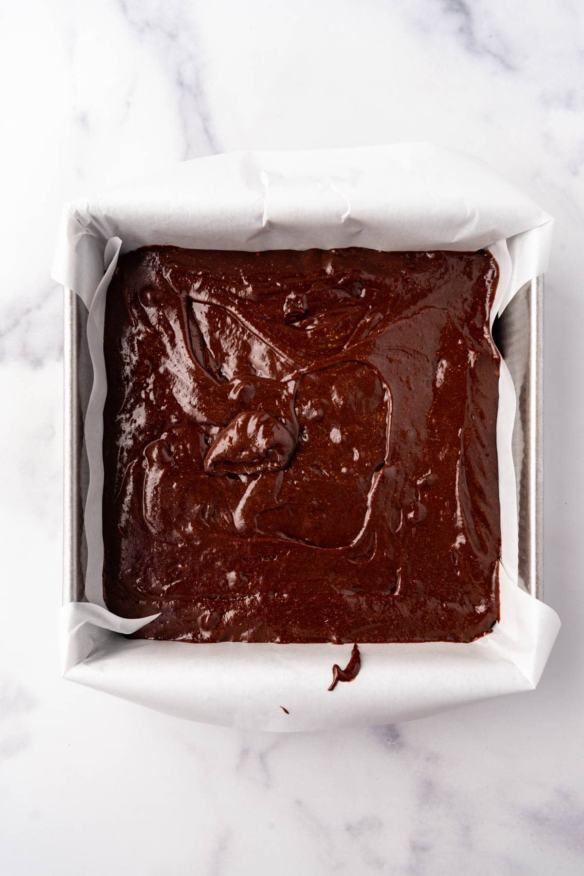 Brownie batter in a square baking pan.