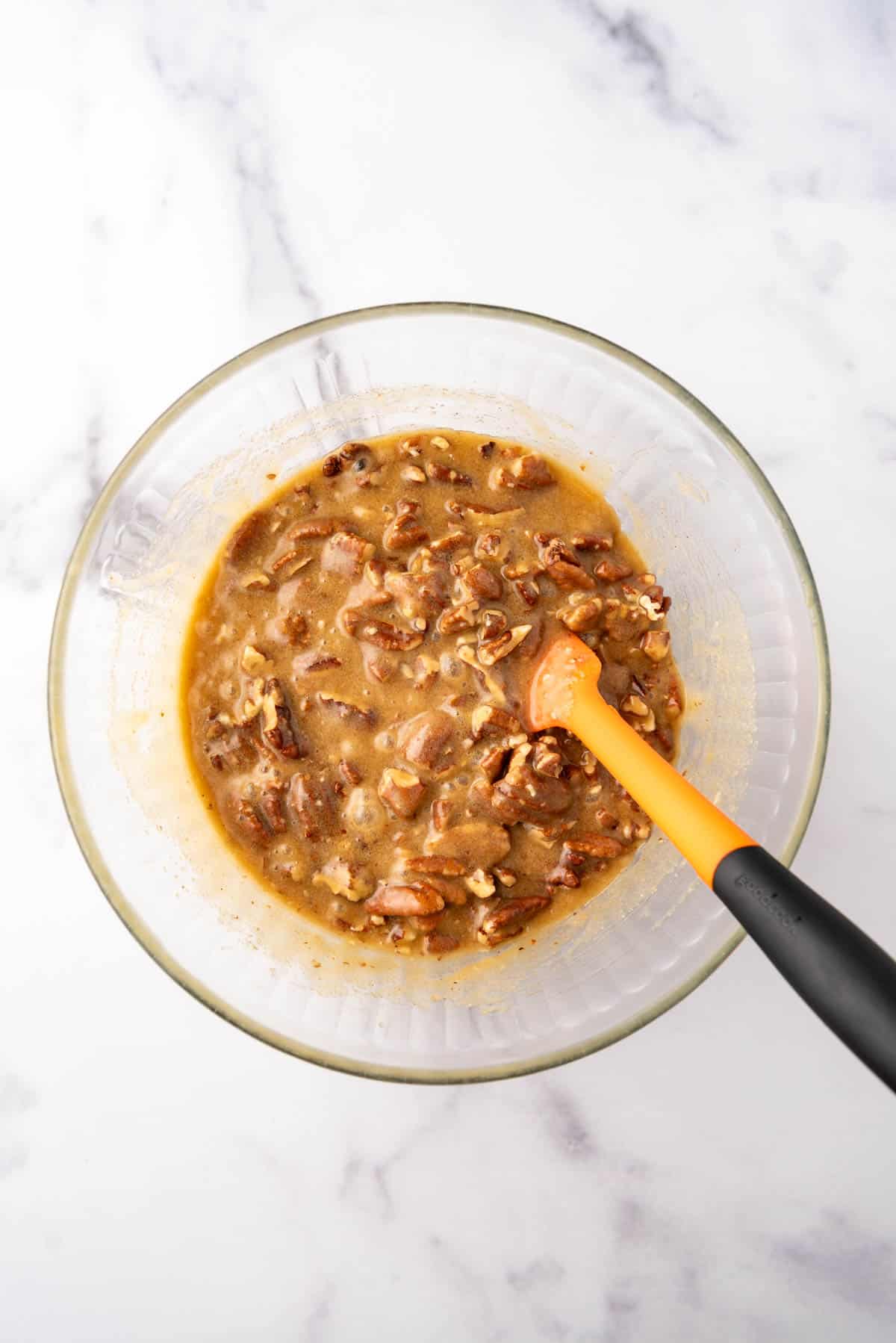Pecan pie filling in a mixing bowl with a spatula.