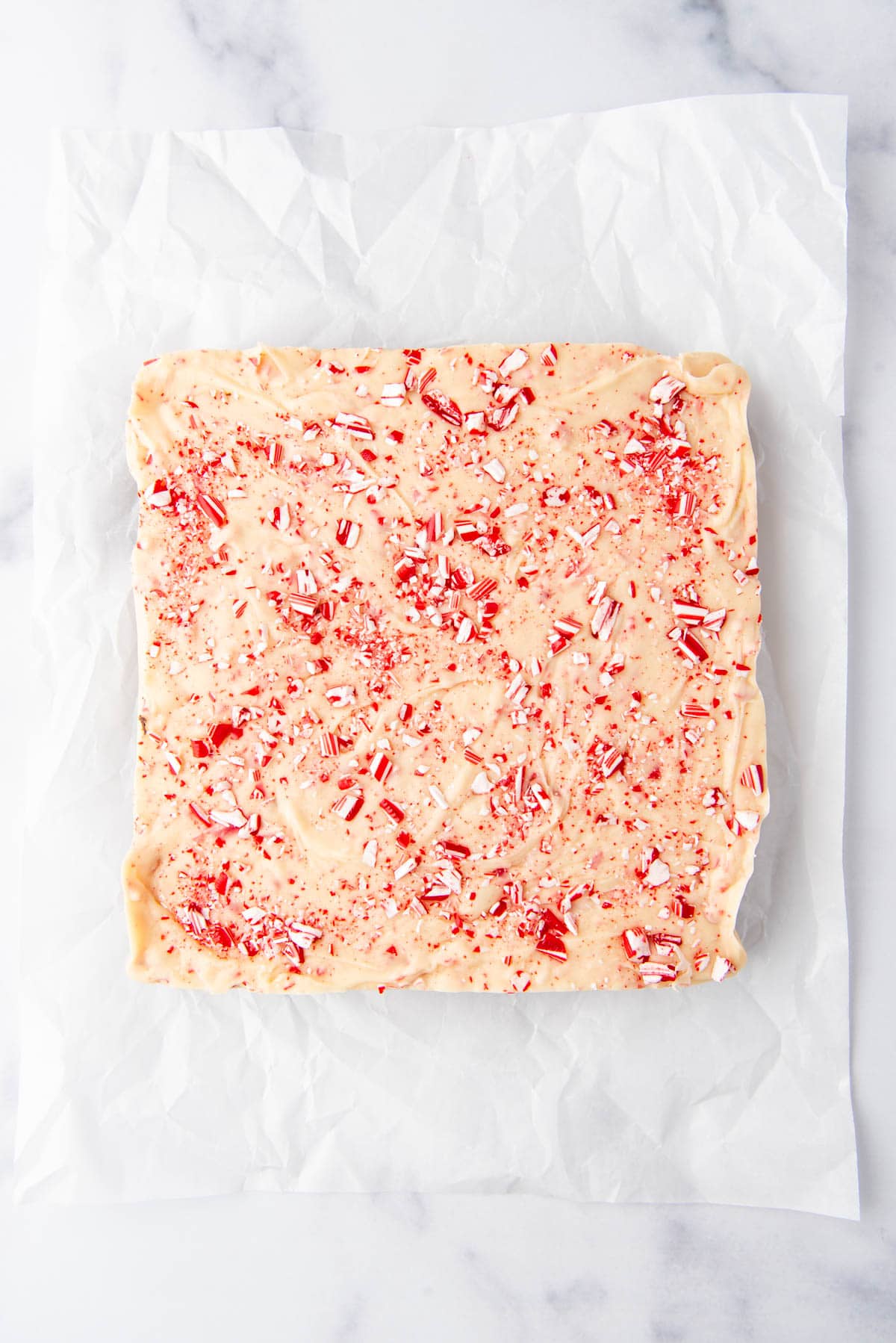 Finished peppermint bark fudge on a white parchment paper sheet.